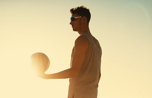 Beach volleyball player serving during coastal championship game at sunset