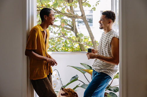 Two friends smiling and chatting in a bright, comfortable home setting
