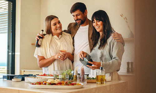 Group of friends enjoying food and drinks in a cozy home kitchen