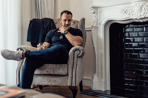 Mature business an sitting in hotel room with a glass of whisky