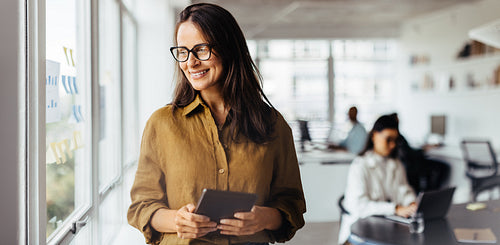 Business woman thinking while holding a tablet