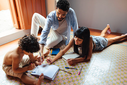 Father guiding children during an educational activity on a tiled floor