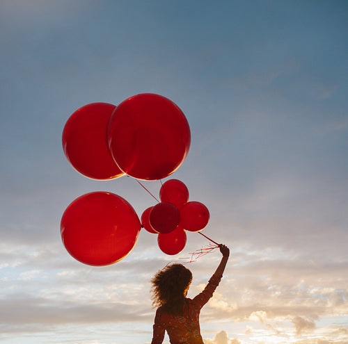 Woman with balloons at sunset