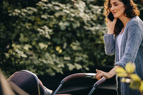 Woman talking on mobile phone while pushing a pram