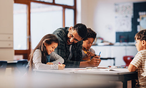 Teacher mentoring primary school children in a class