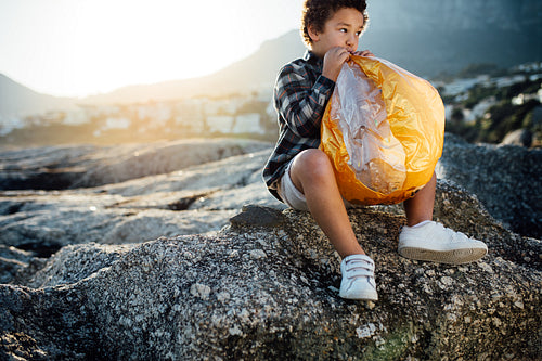 Boy blowing a balloon sitting on the rocks