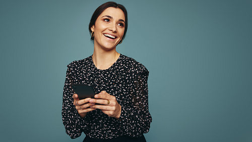 Cheerful young woman holding a mobile phone in a studio