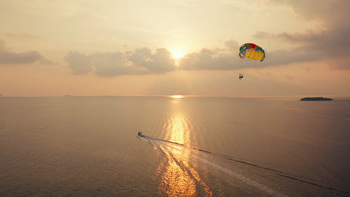 Parasailing during a spectacular sunset creating golden reflections on water