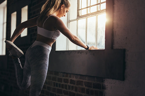 Strong woman stretching her leg at gym
