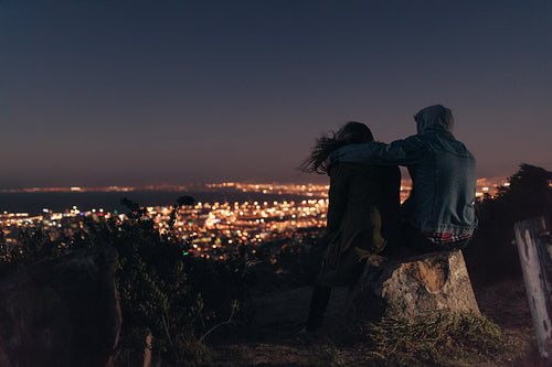 Rear view of couple sitting together on a tree trunk