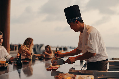Chef performing a teppanyaki show at an outdoor scenic dining setting