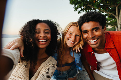 Group of cheerful friends taking a selfie at sunset outdoors
