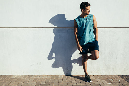 Healthy young runner standing by a wall