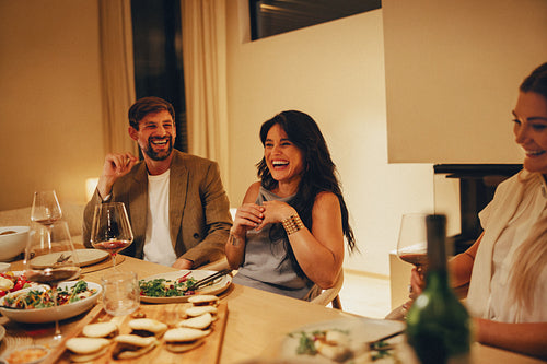 Friends sharing laughter and meals around a warm dining table