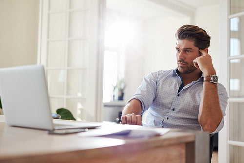 Businessman at home office looking at laptop and thinking