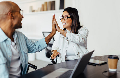 Business people giving each other a high five in an office