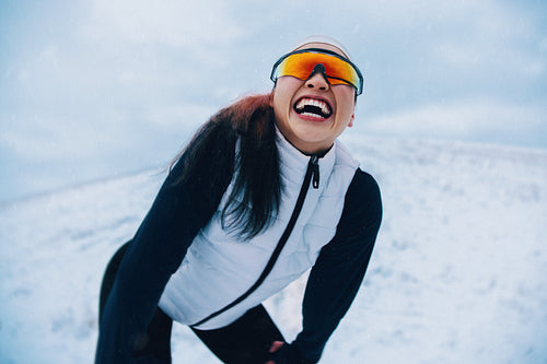 In a snowy outdoor scene, the woman takes a rest after running in winter