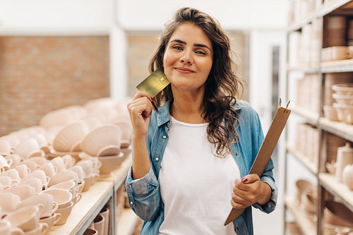 Ceramic shop owner holding a credit card in her store