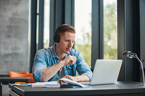 Student studying with books and laptop in library