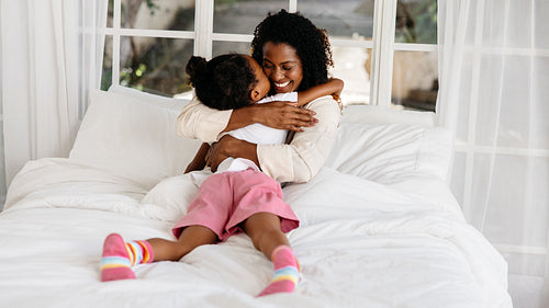 Loving mother hugging daughter in bed