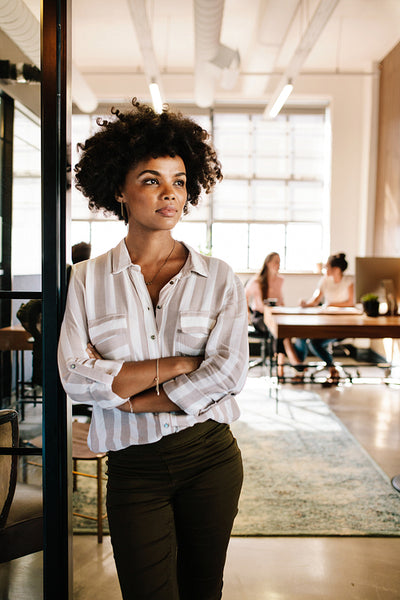Thoughtful woman at office doorway and looking away