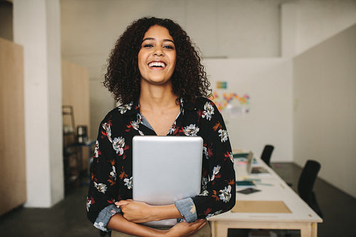 Portrait of a smiling businesswoman in office holding a laptop