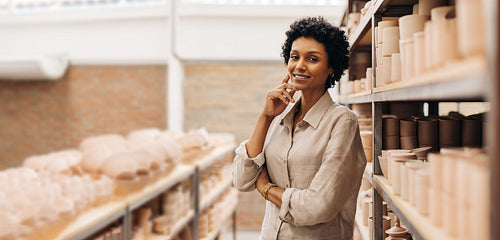 Cheerful female ceramist smiling at the camera in her store