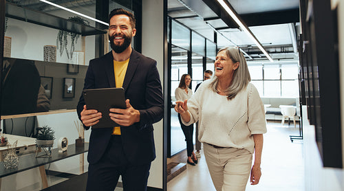 Laughing entrepreneurs walking together in an office