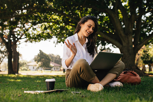 Woman at park having a video conference call on her laptop