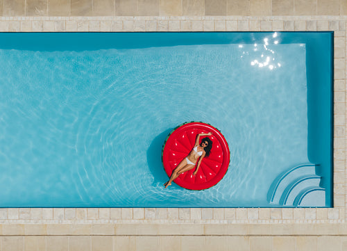 Young woman floating on inflatable mattress in pool