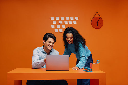 Professional colleagues brainstorm ideas on laptop in vibrant office setting
