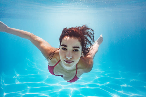 Woman swimming underwater in pool