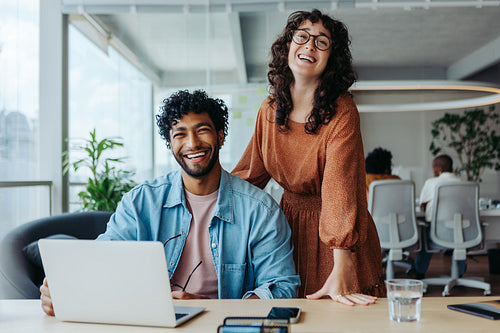 Two happy business people working together in a collaborative office environment