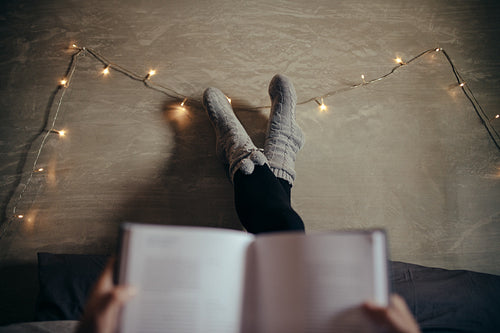 Woman lying on bed with a book