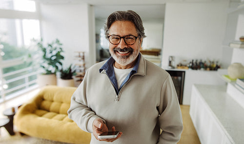 Senior man holds a smartphone at home