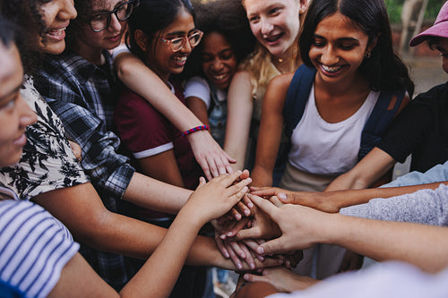 Group of multicultural teenagers putting their hands together in solidarity