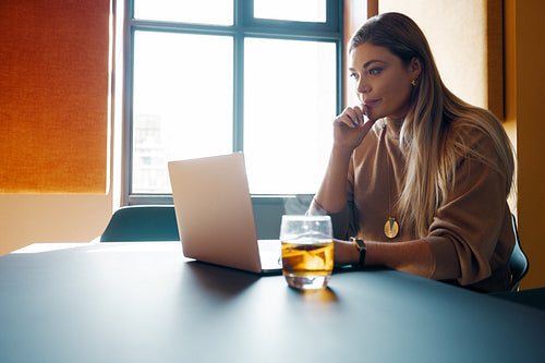 Woman working on a laptop in a modern sunlit workspace