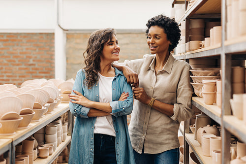 Successful businesswomen smiling at each other in their ceramic store