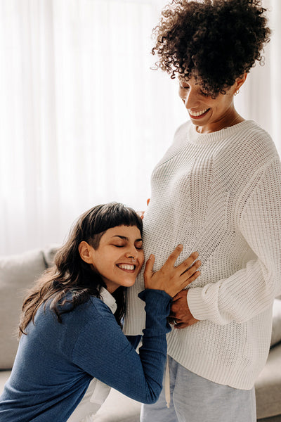 Excited young woman listening to her wife's belly bump