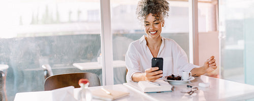 Successful businesswoman reading a text message in a cafe