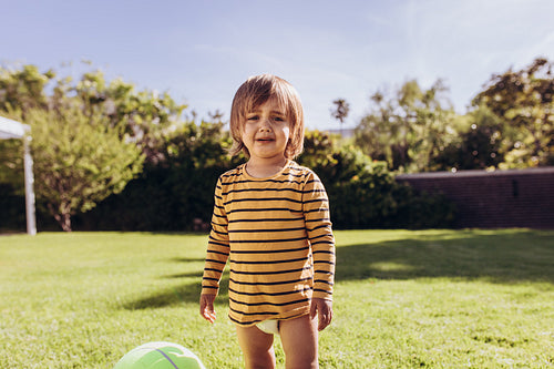 Kid standing in a park beside a ball