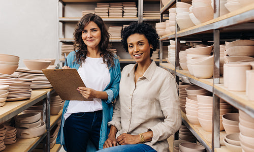 Two happy young ceramists working together in their shop