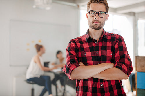Confident young entrepreneur standing in office