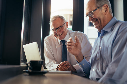 Cheerful business men with laptop at cafe