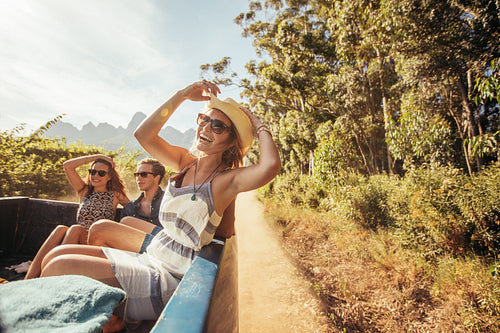 Cheerful young woman with friends in the back of a pickup truck