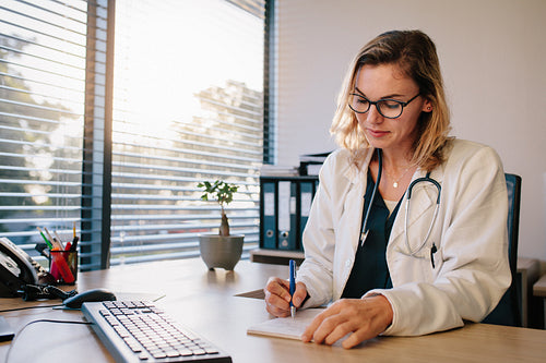 Female doctor sitting at the desk and writing