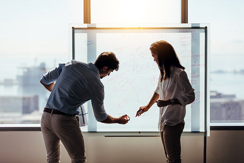 Colleagues making business plans on whiteboard in office.