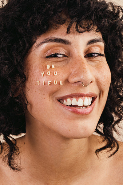 Woman smiling with the word "BEAUTIFUL" written on her face