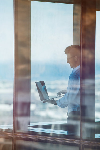 Businessman near window using laptop