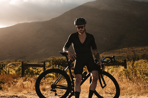 Bicycle rider taking a break on country road.